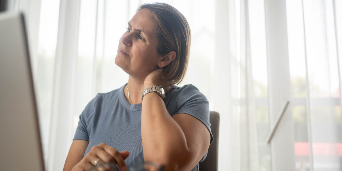 Woman at desk with hand on neck