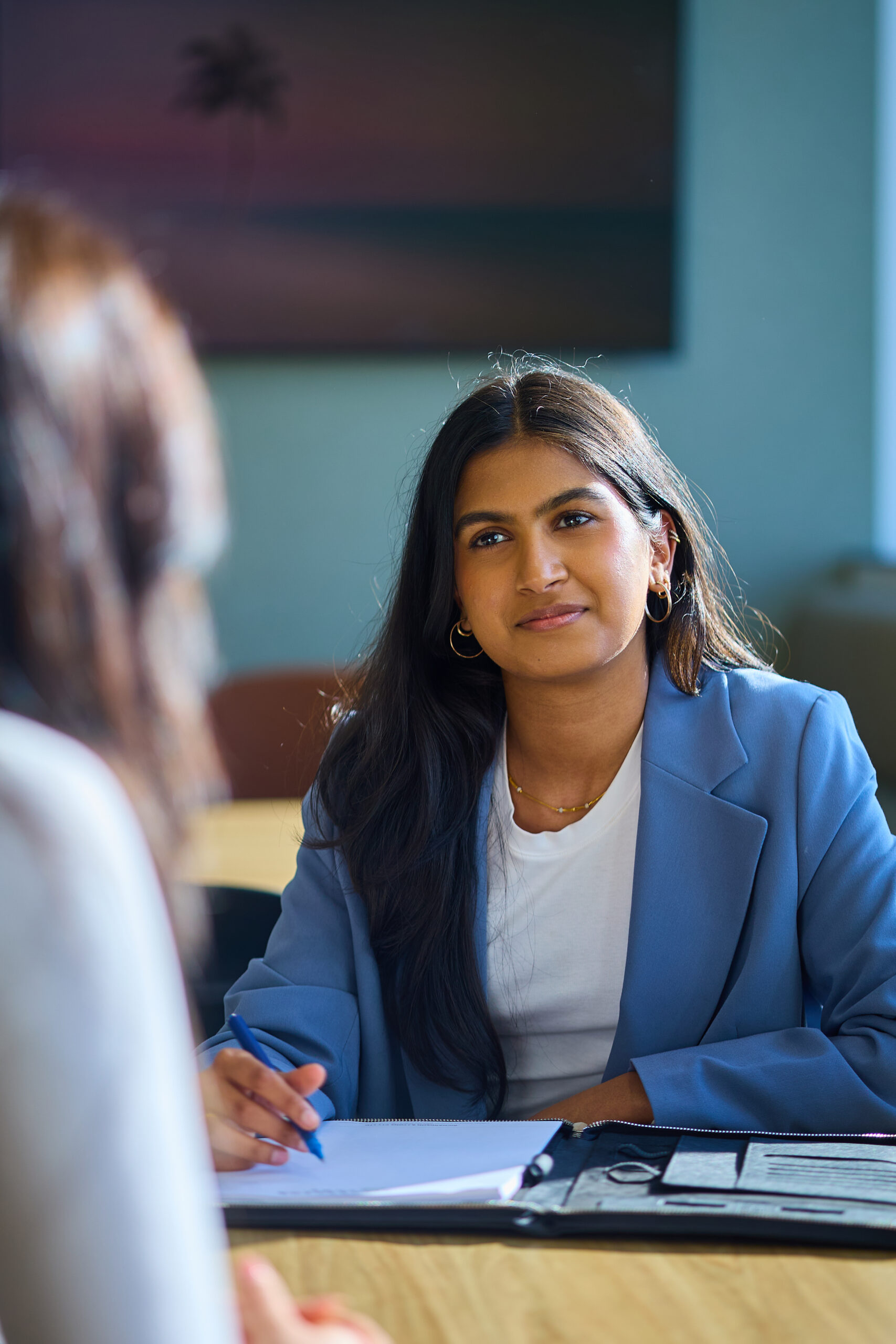 Solicitor attentively discusses Queensland work injury damages claims with client at a well-lit office table.